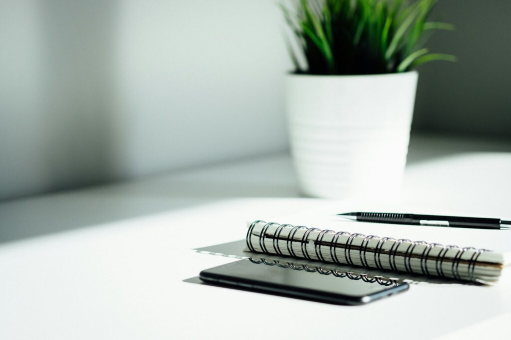 A pen, notebook and smartphone on a table, ready for planning a business