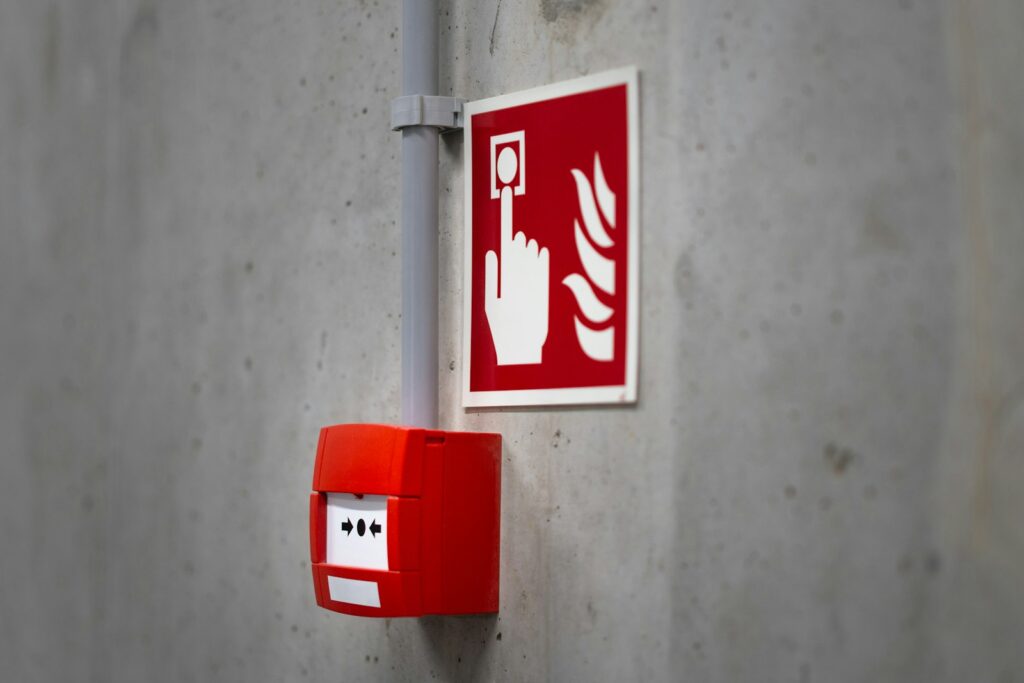 Red fire alarm button on a concrete wall inside an industrial building, ready to be triggered