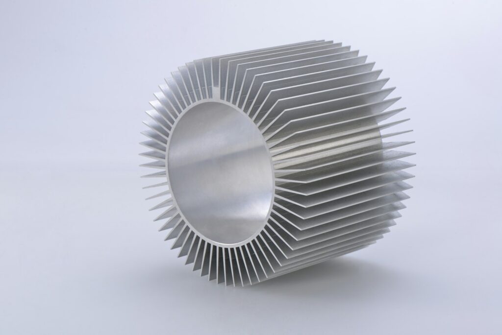 Silver round aluminium extrusion on a white surface, an example of a machined aluminium part