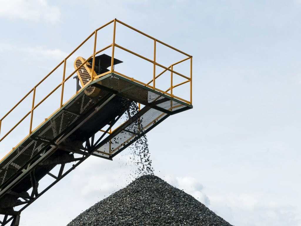 A large pile of gravel being loaded onto a truck, typical of abrasive bulk material handling