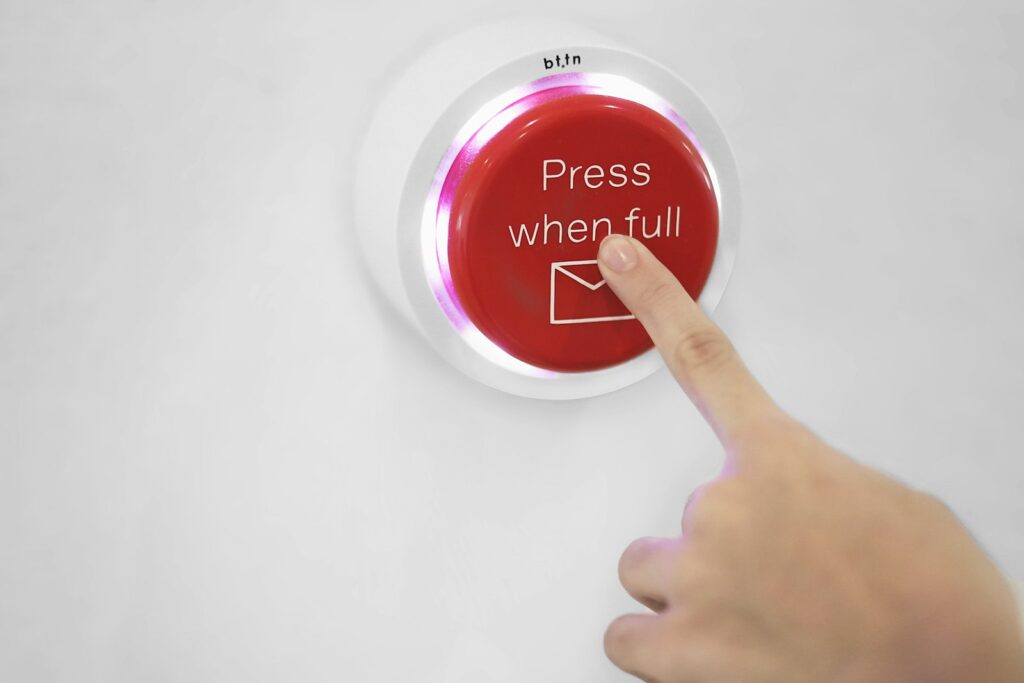 A hand pressing a round red button mounted on a wall
