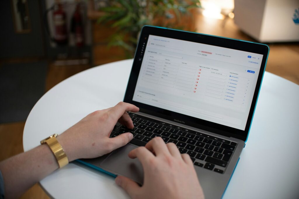 Hands typing on a laptop with a data spreadsheet on screen