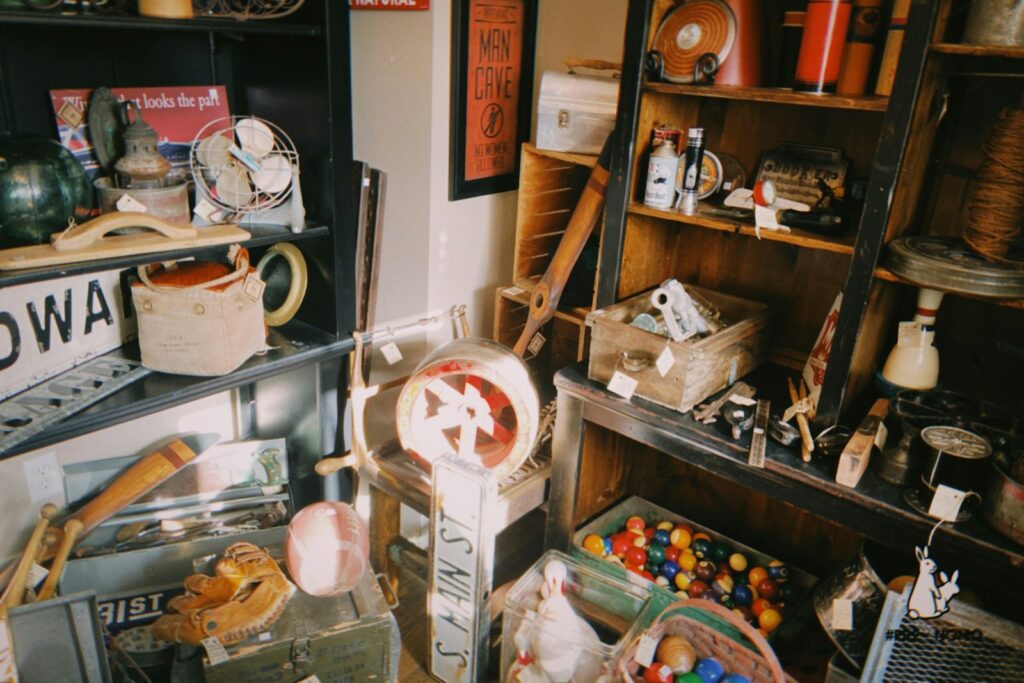 Shelves and floor filled with vintage items including billiards, baseball gloves, street signs and books