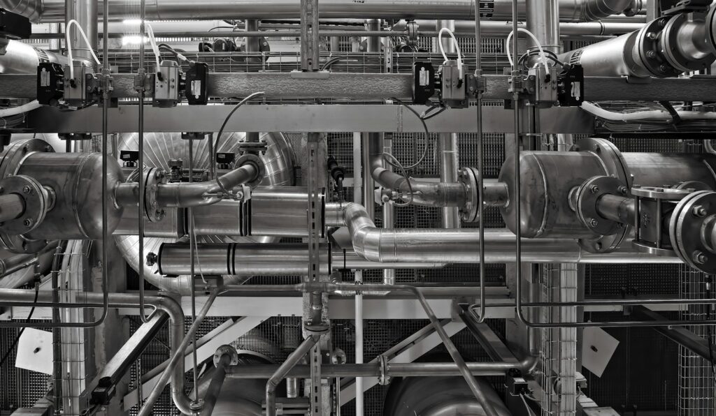 Network of industrial metal pipes and valves in a factory setting